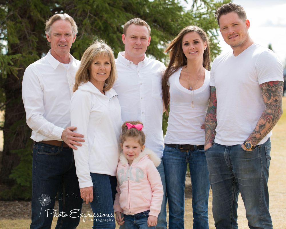 Family group wearing coordinated white shirts poses casually outdoors.