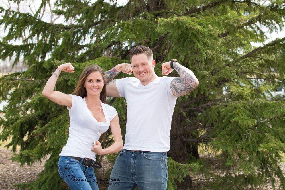 Playful outdoor photo session with people jumping and posing near evergreen trees.