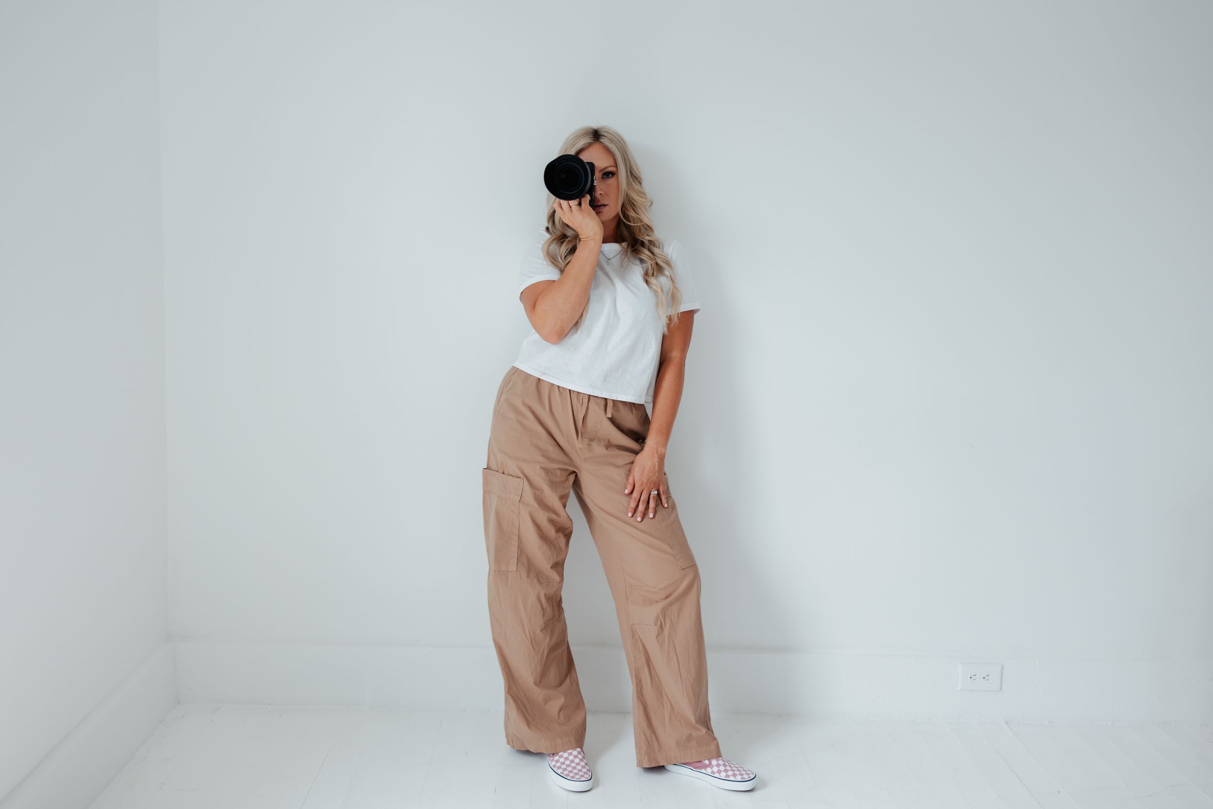Stylish person in casual wear posing against white background with camera.