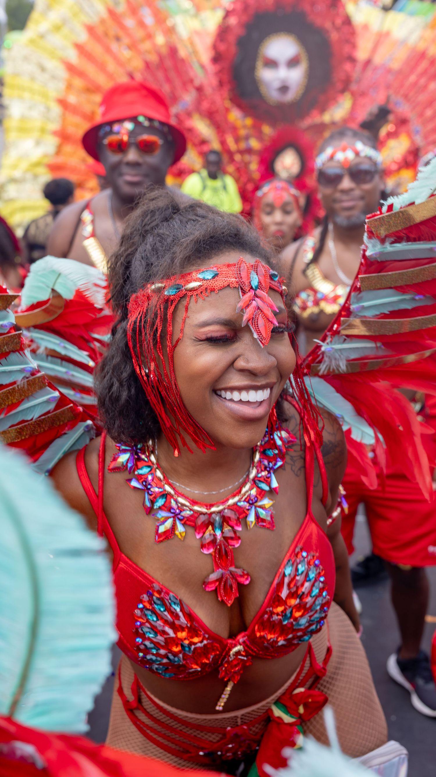 Festival performers in bright red feathered carnival costumes dancing during a celebration.