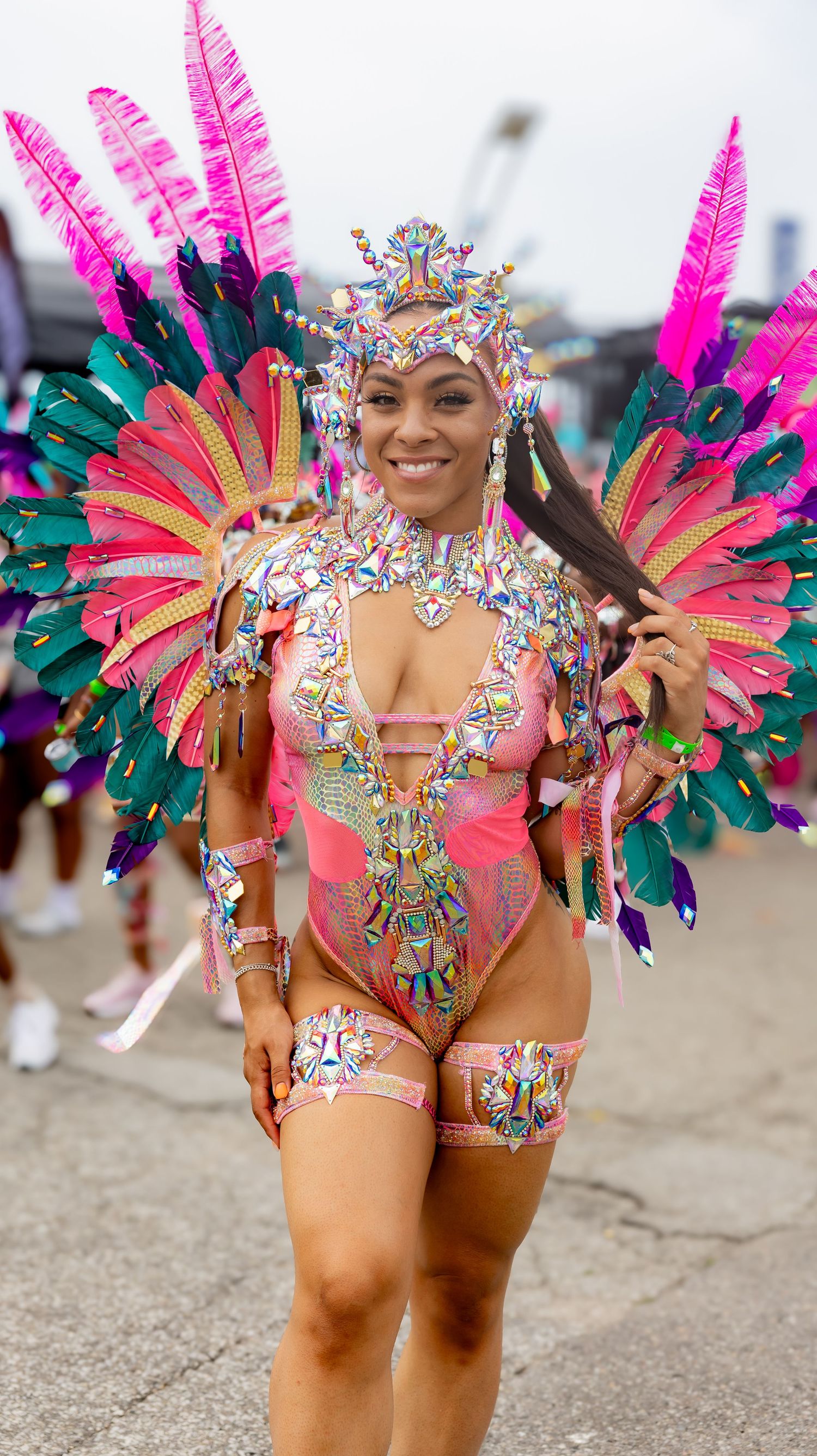 Colorful carnival dancer wearing vibrant pink feathers and sequined costume performing at a festival.