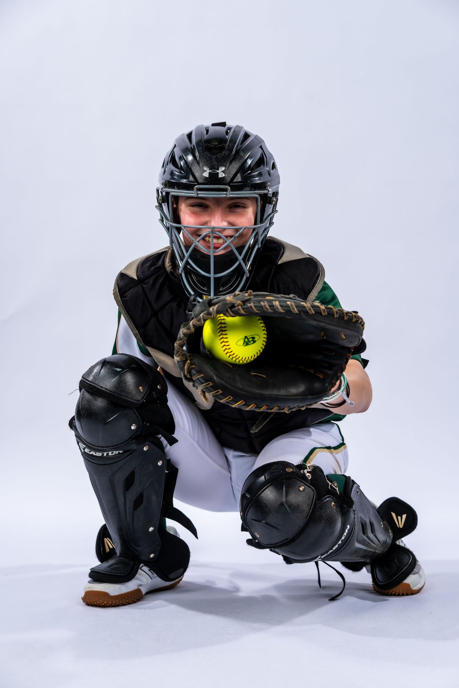 A catcher from the Absolute Blast Fast Pitch softball team posing in her catcher gear with a ball in her glove.