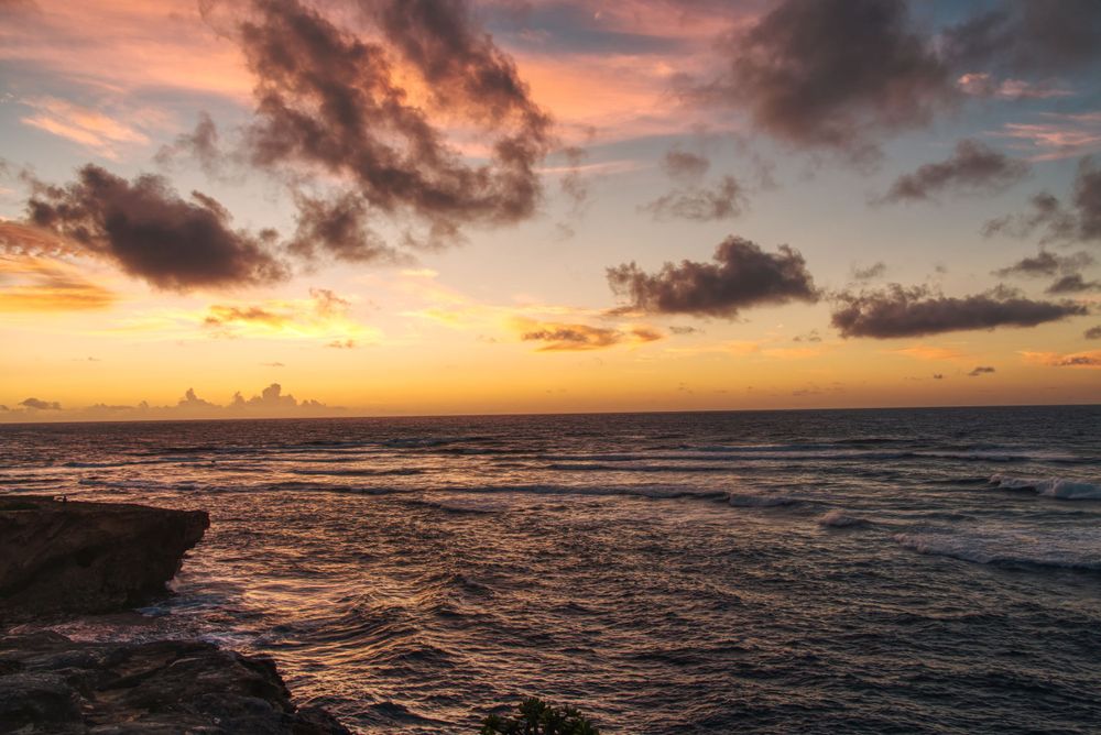 A dramatic sunrise over a beach with beautiful clouds.