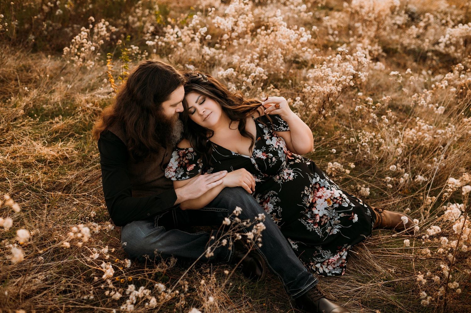 a husband and wife cuddle in a field of flowers