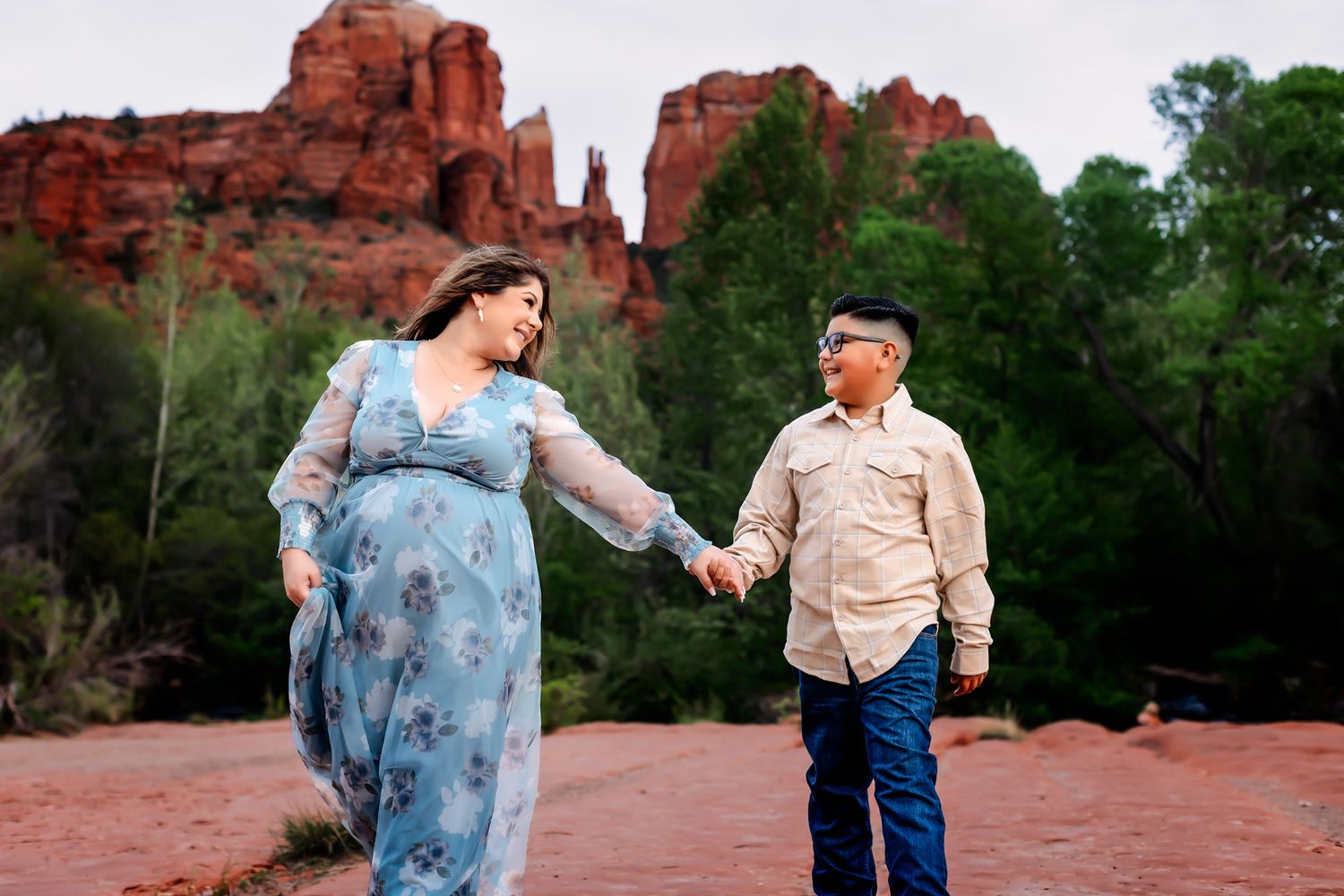 pregnant mother with son smiling and holding hands with a beautiful landscape of the Sedona red rocks in the background