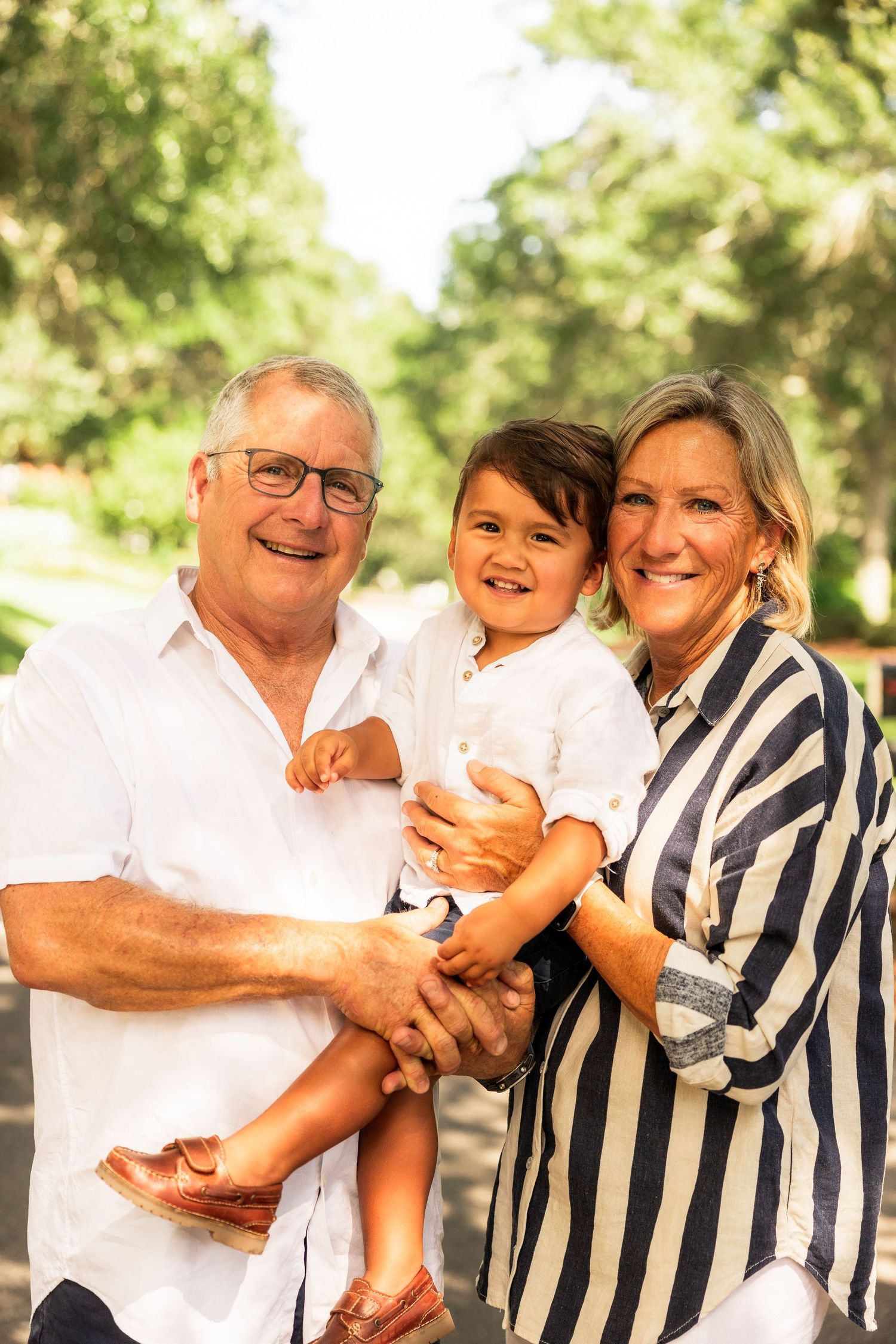 Grandparents holding their grandson while smiling for a photo