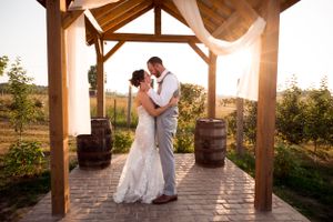 Bride and groom during golden hour embracing each other under their alter arch. Timeless and romantic.