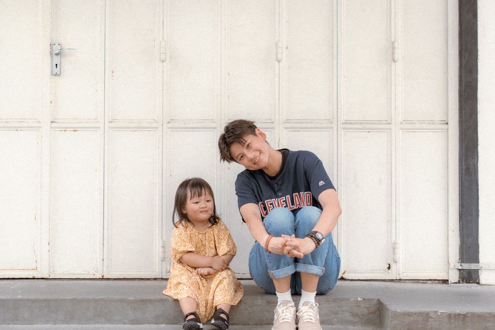 Two people sit together on white doorstep sharing a casual moment.
