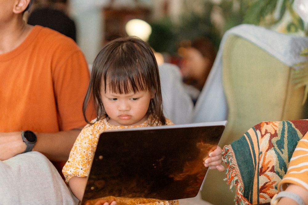 Young child in yellow top looking at tablet screen while sitting.