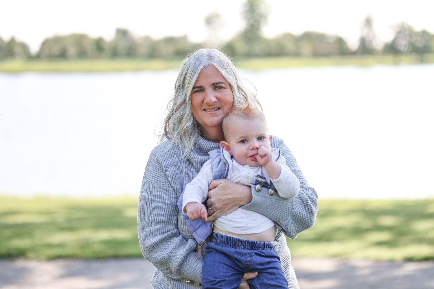 Casual outdoor portrait by lake with baby on sunny day.
