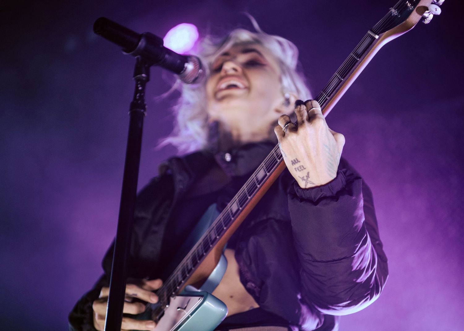 Lights playing guitar and singing into the microphone. The camera is focused on her hand playing guitar.