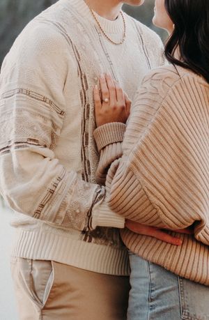 Close-up partial view showing light beige knit sweater textures and light denim in intimate embrace poses.