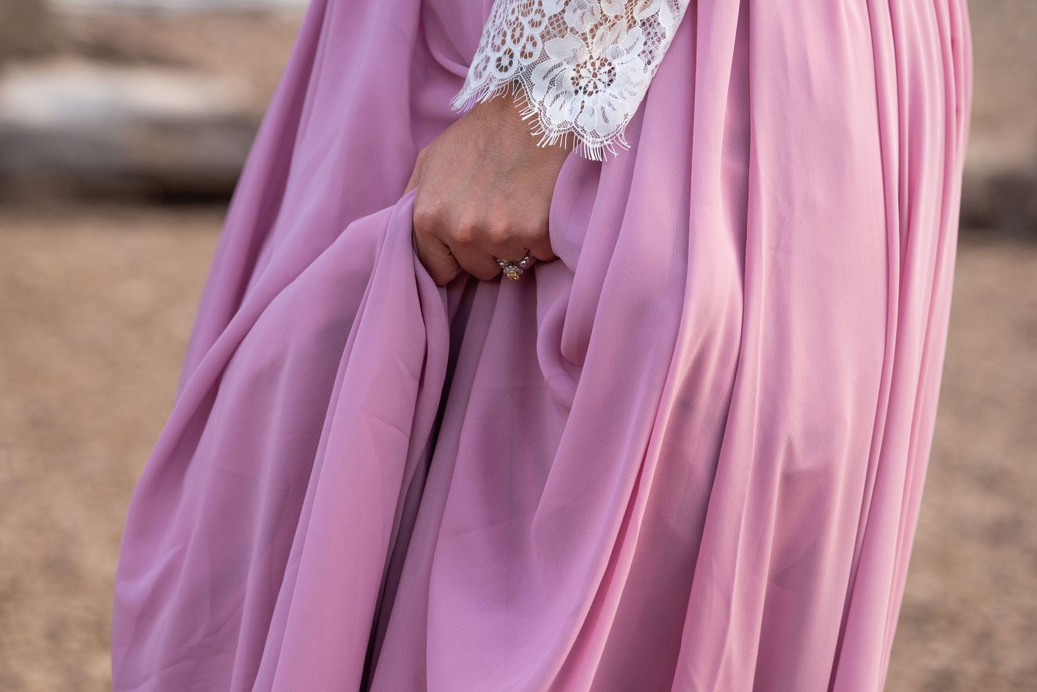 Close-up detail of a pink flowing dress with lace sleeve detail.