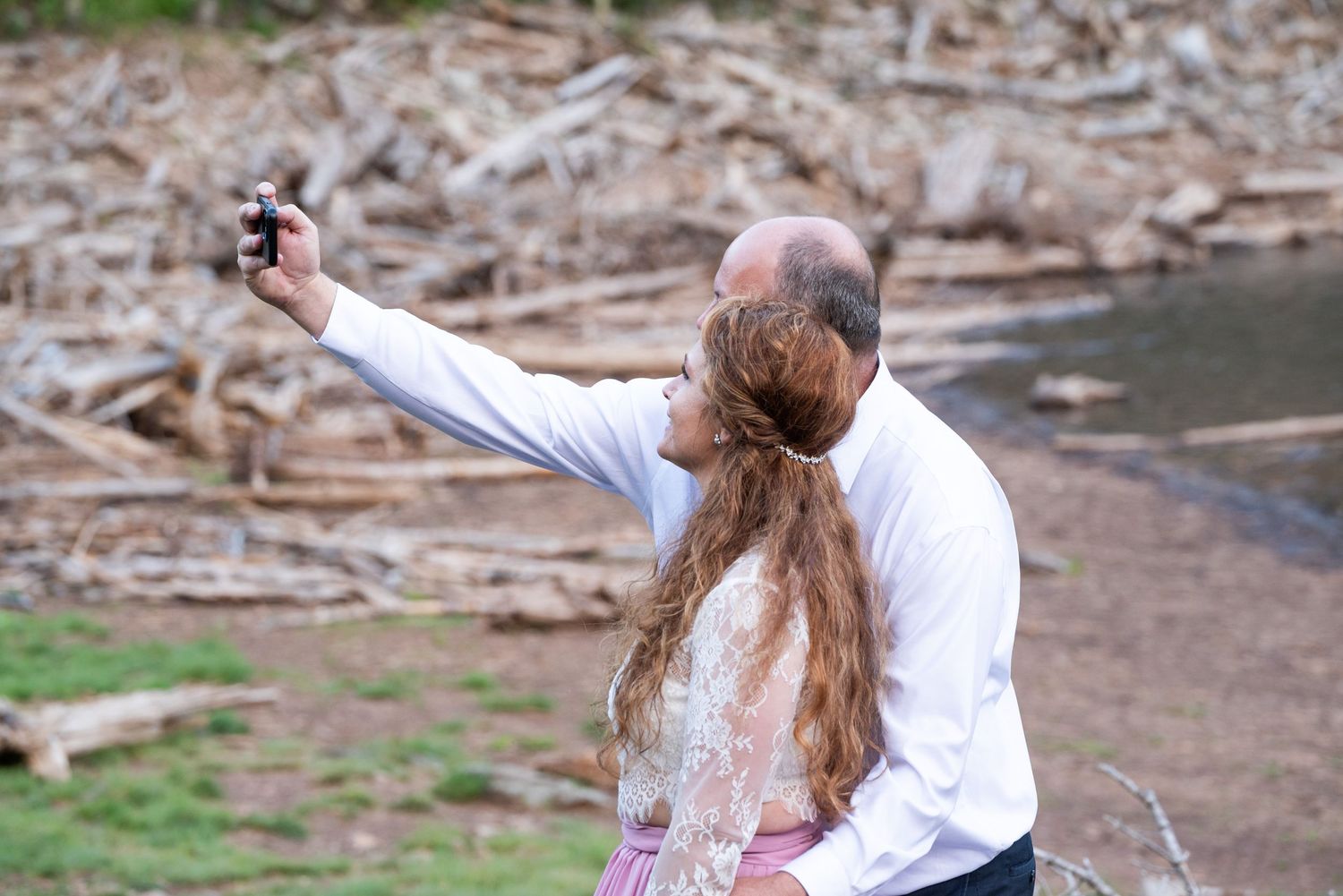 A couple embraces during an intimate outdoor wedding ceremony in a mountainous forest setting.