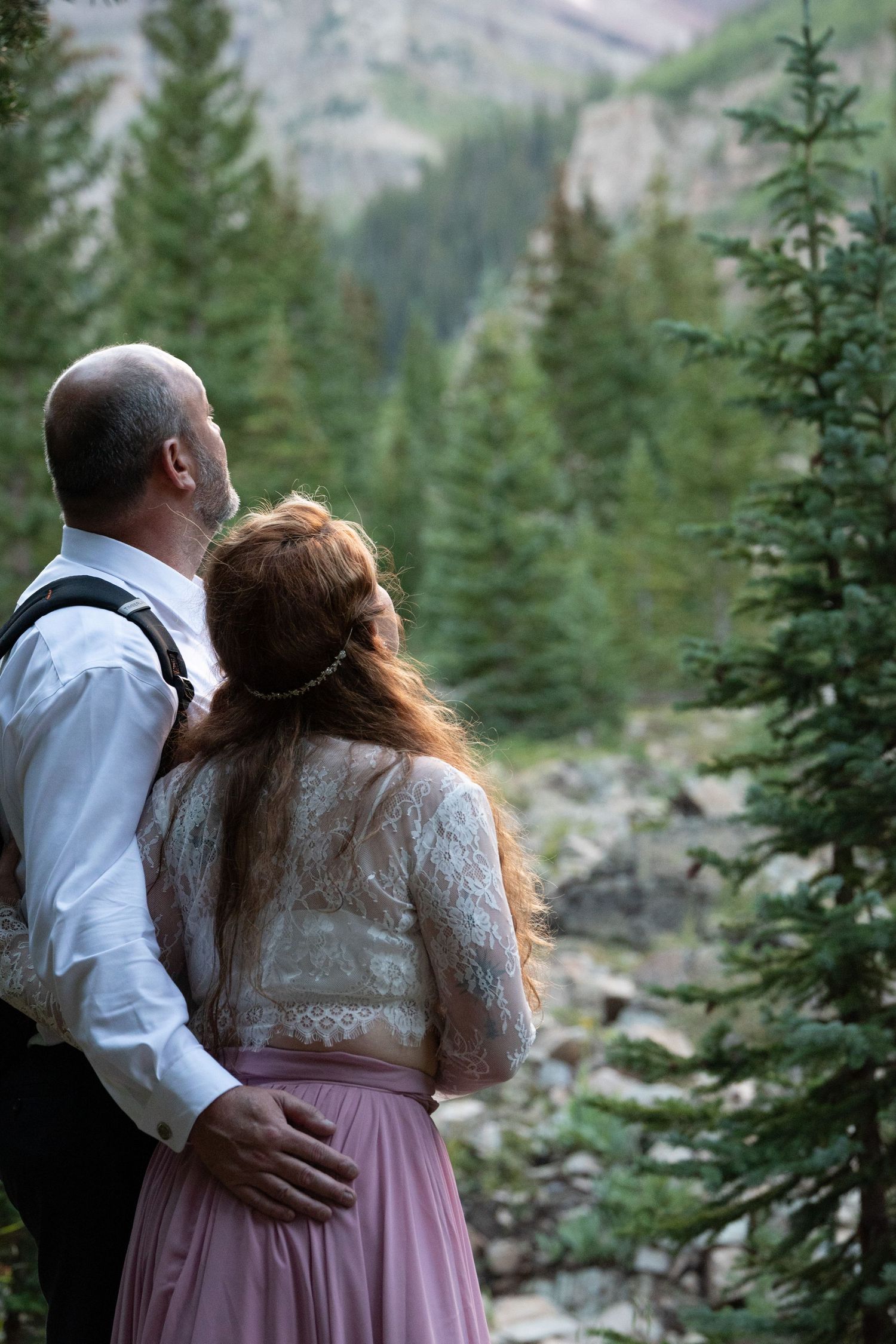 A romantic mountain elopement with evergreen trees and rugged peaks in the background.
