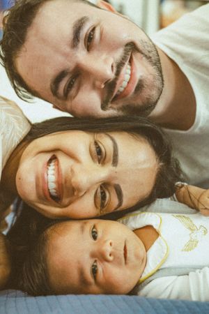 A joyful family photo with everyone smiling together on a bed.