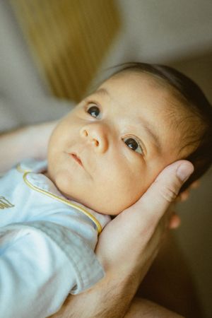 Close up portrait of a baby in light blue clothing looking at the camera.