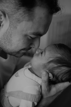 Intimate black and white portrait of parent and baby sharing a gentle moment.
