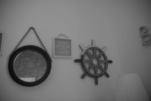 Nautical themed wall decor featuring a round mirror and ship's wheel.