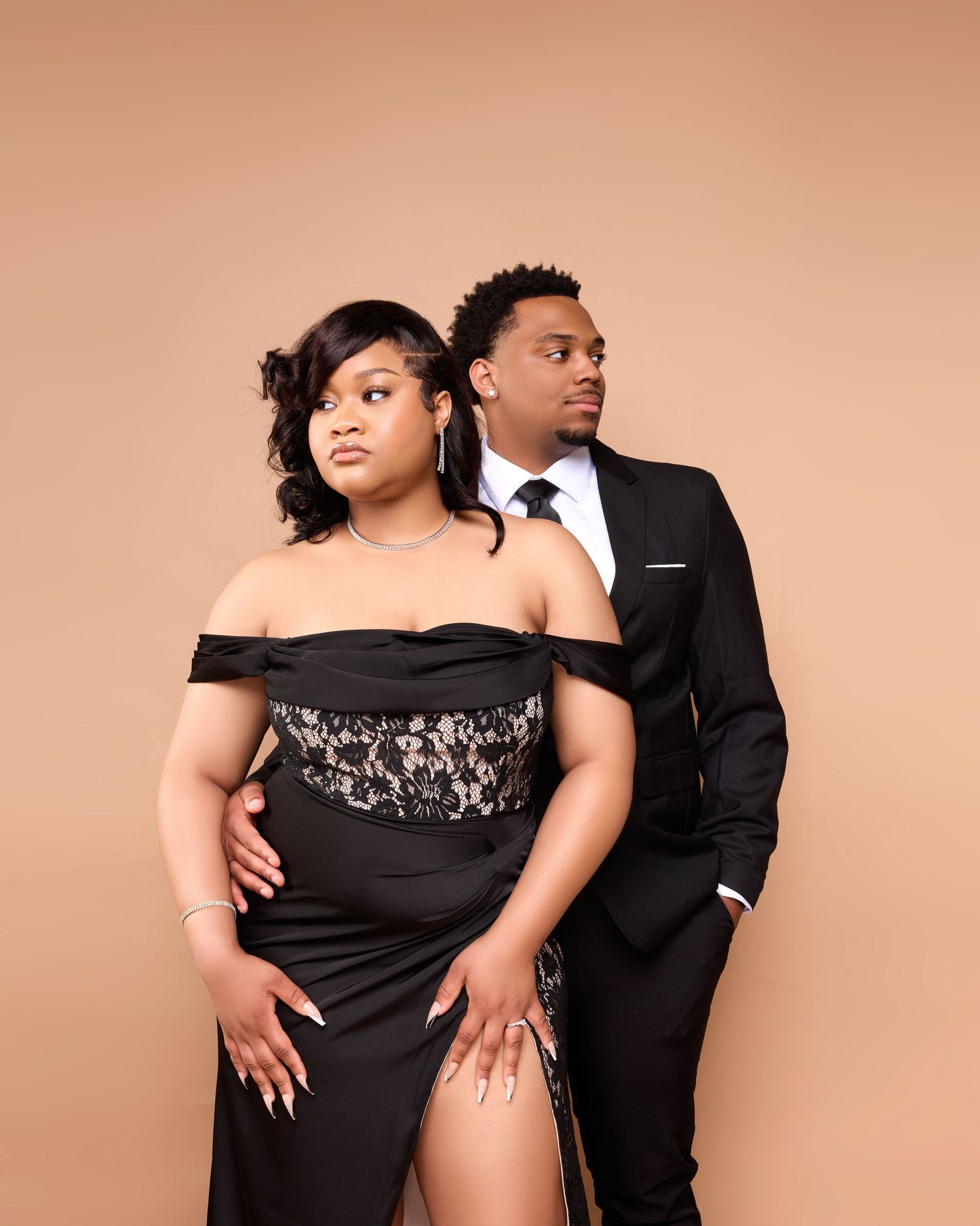 Professional studio portrait of two people in burgundy and gray formal wear against dark background.