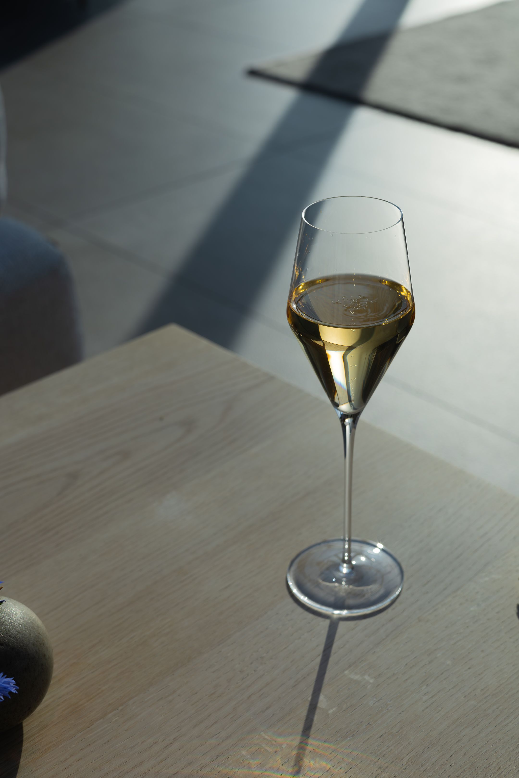 White wine in elegant stemmed glass on wooden table with dramatic lighting.