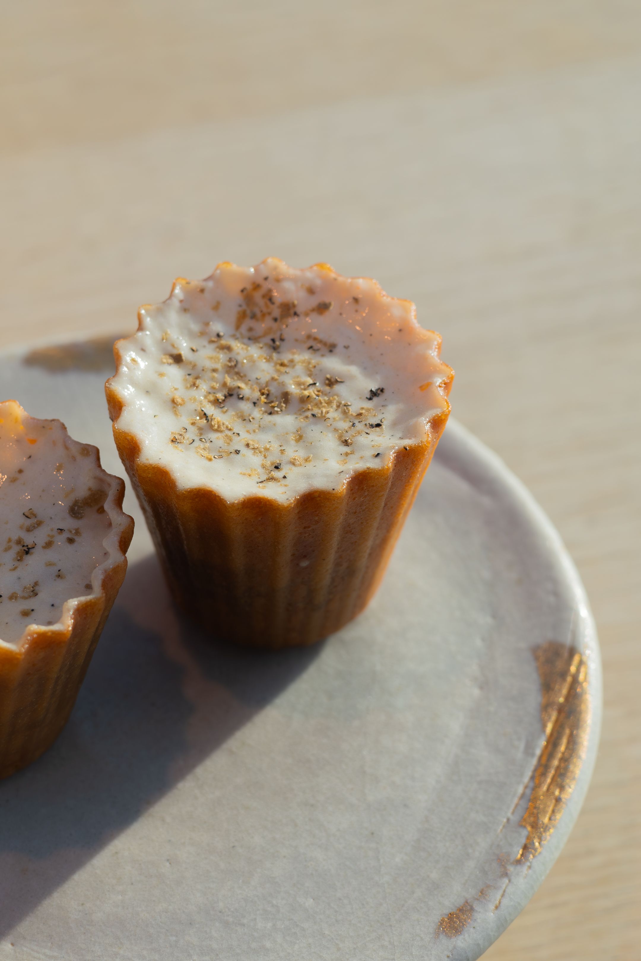 Artisanal cupcake with white frosting and spice garnish on ceramic plate.