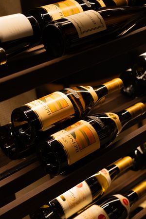 Premium wine bottles with golden labels arranged diagonally on wooden cellar shelves.