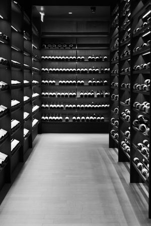 Black and white image of a modern wine cellar with symmetrical bottle storage.