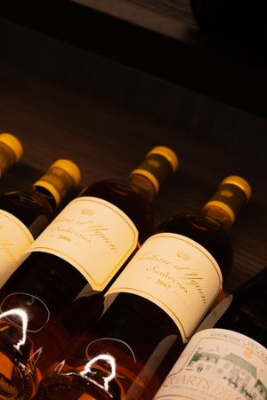Golden-labeled wine bottles illuminated against dark wood in luxury wine storage.