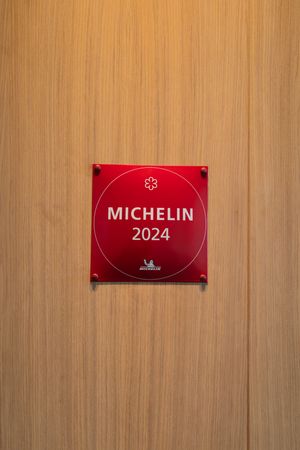 Red Michelin 2024 plaque mounted on a light wooden wall.