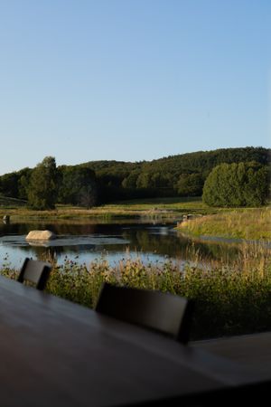 Tranquil pond view from restaurant window with hills and trees in golden evening light.
