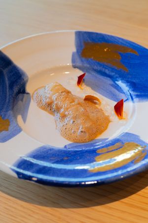 Delicate pastry garnished with red accents on a blue and white artistic ceramic plate.