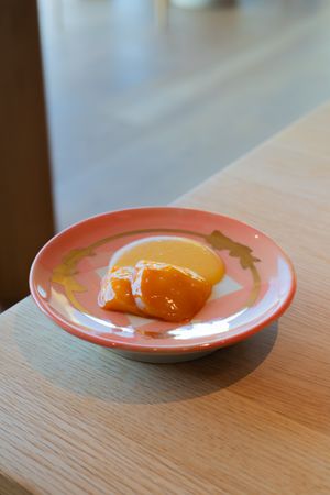Orange segments served on a decorative coral-colored plate with gold accents on a wooden table.