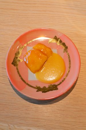 Fresh orange segments arranged on a pink plate with golden decorative pattern.