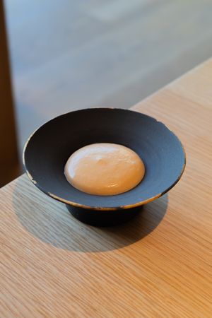 A white spherical dessert served in a sleek black concave bowl.