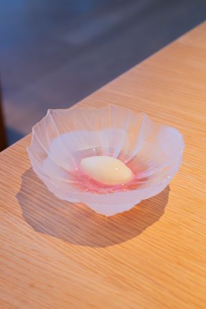 Delicate dessert presented in a translucent pink flower-shaped bowl on wooden surface.