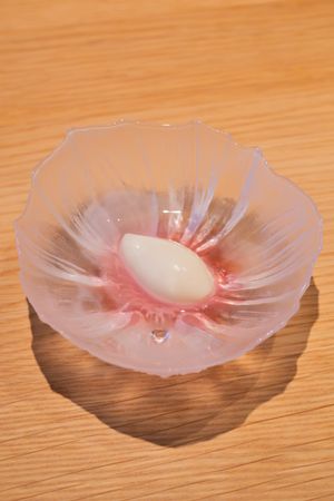 White dessert sphere nestled in a pink-tinted translucent flower-shaped dish.