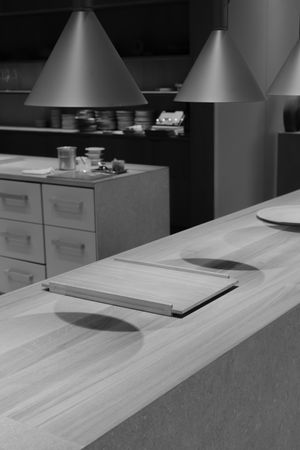 Black and white overhead view of modern light fixtures above a counter workspace.