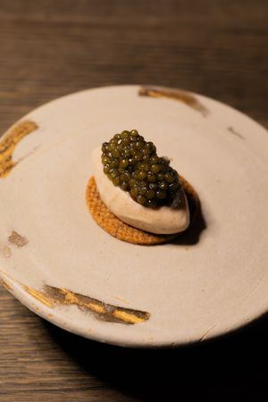Caviar elegantly presented on a cream-colored dish with gold accents.
