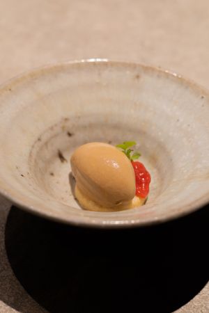 Small dessert with a red garnish served in a rustic ceramic bowl.