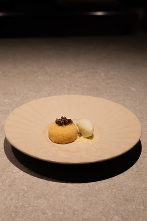 Elegant plated dessert with caviar and ice cream on a beige plate.