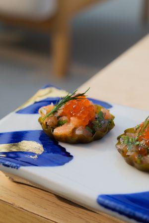 Gourmet appetizer with salmon roe and dill on decorative blue and white plate.