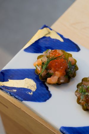 Elegant seafood appetizer with caviar and herbs on artistic blue and white ceramic plate.