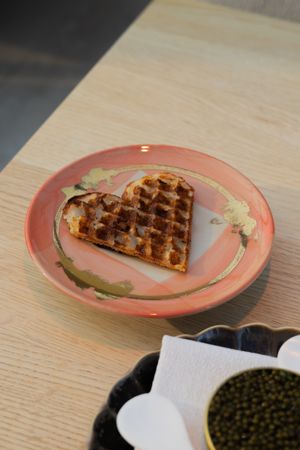 Heart-shaped waffle on pink decorative plate with gold accents.