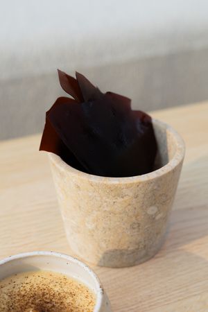 Dark chocolate decoration pieces arranged in a textured ceramic vessel.