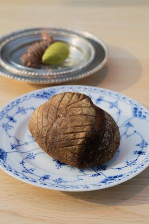 Dark crusty artisanal bread loaf on blue and white patterned plate.