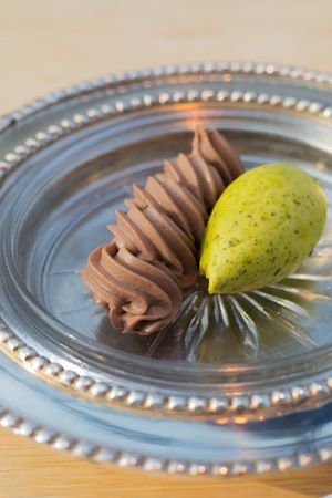 Chocolate mousse swirl and fresh pear arranged on silver decorative plate.