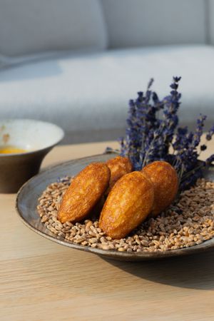 Golden pastries served on seeds with decorative dried lavender sprigs on ceramic plate.