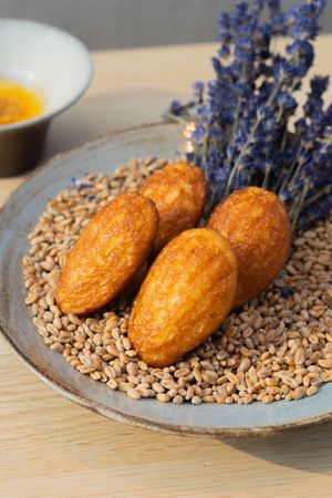 Crispy golden pastries arranged on bed of seeds with fresh lavender garnish.