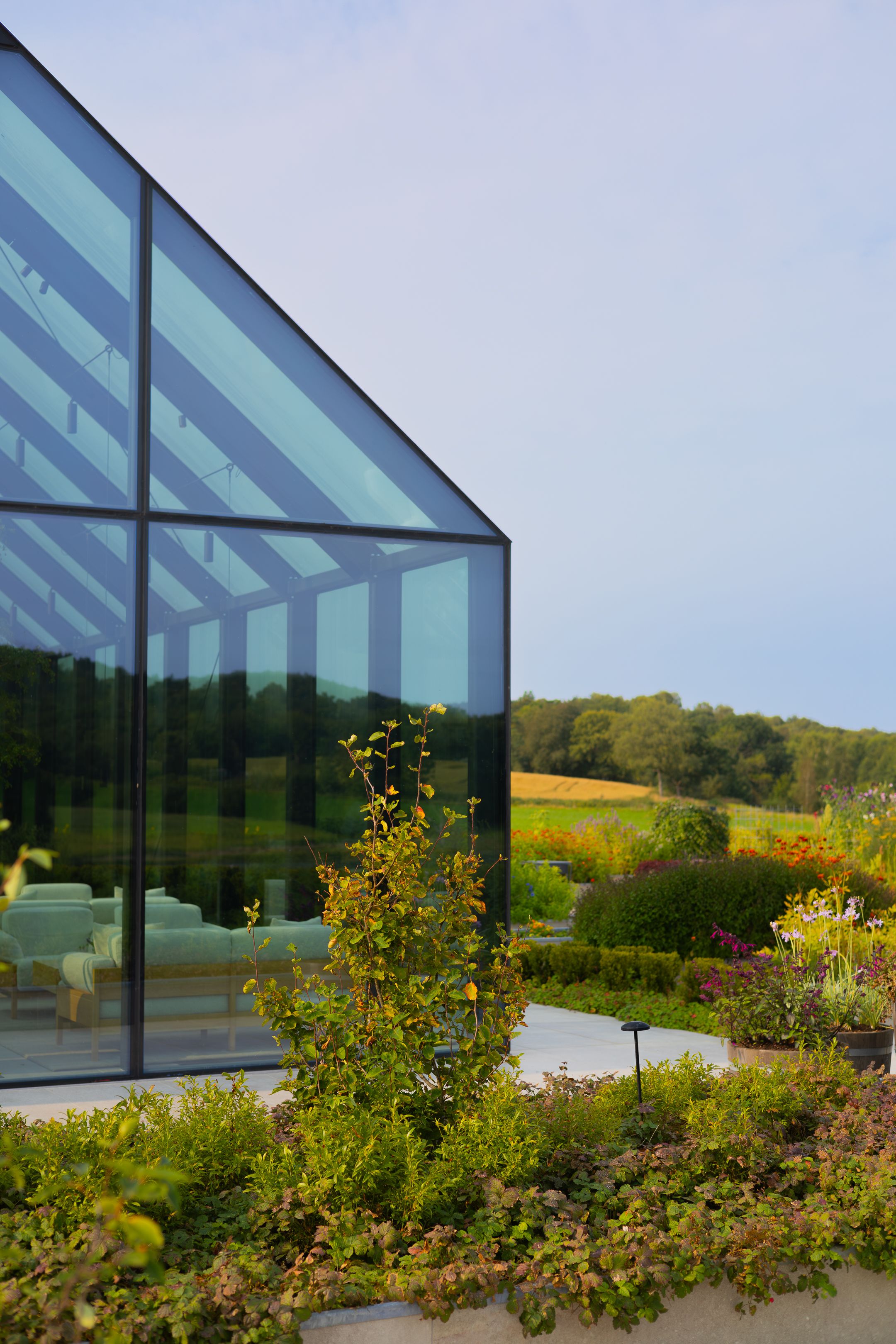 Contemporary glass building with landscaped gardens and rolling hills in the background.